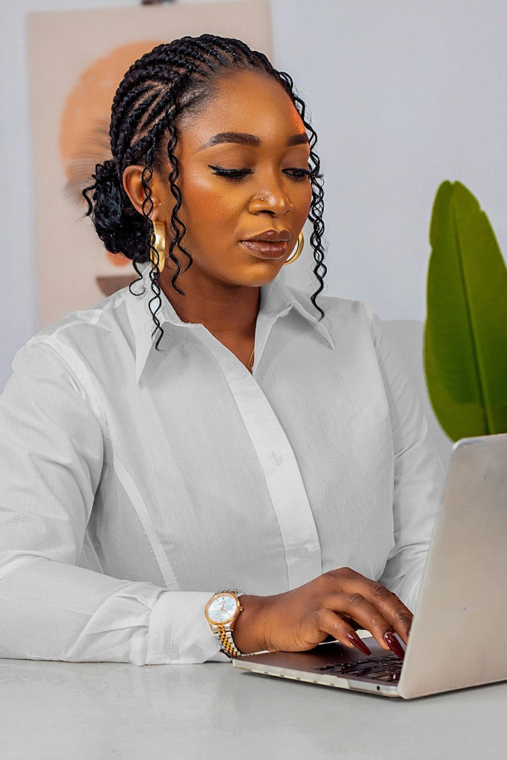 woman with braids wearing a whit shirt and working on a laptop how to style natural hair for an interview