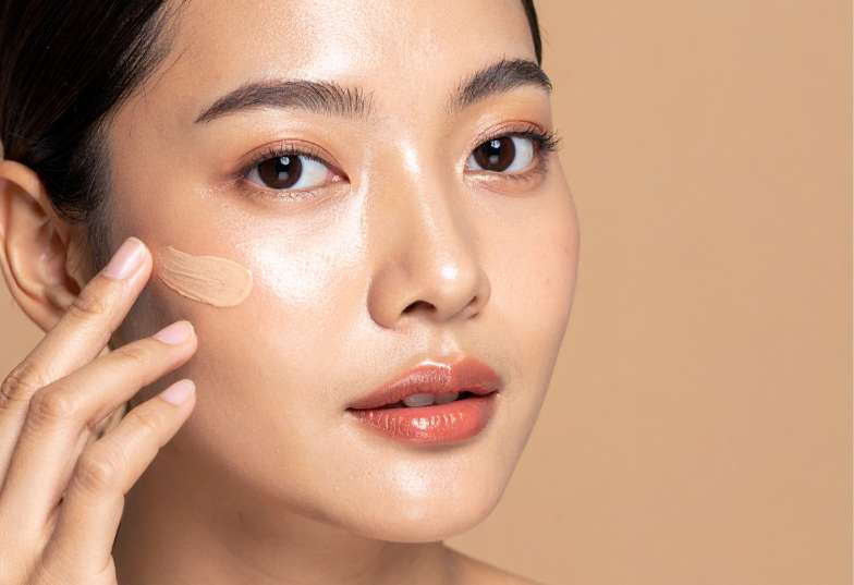 A lady applying foundation as the second step for make up