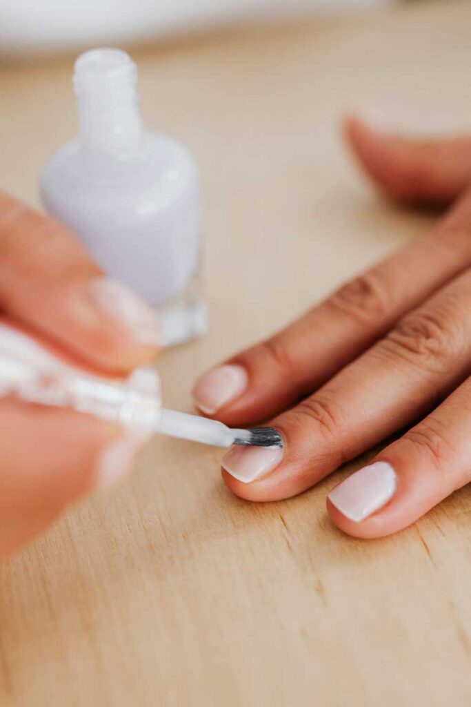 Applying of base coat on someone's nails
