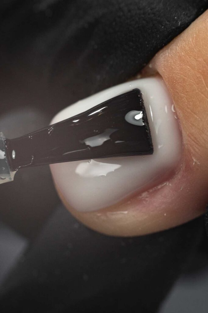 A picture of nail coat gel being applied on the gel
