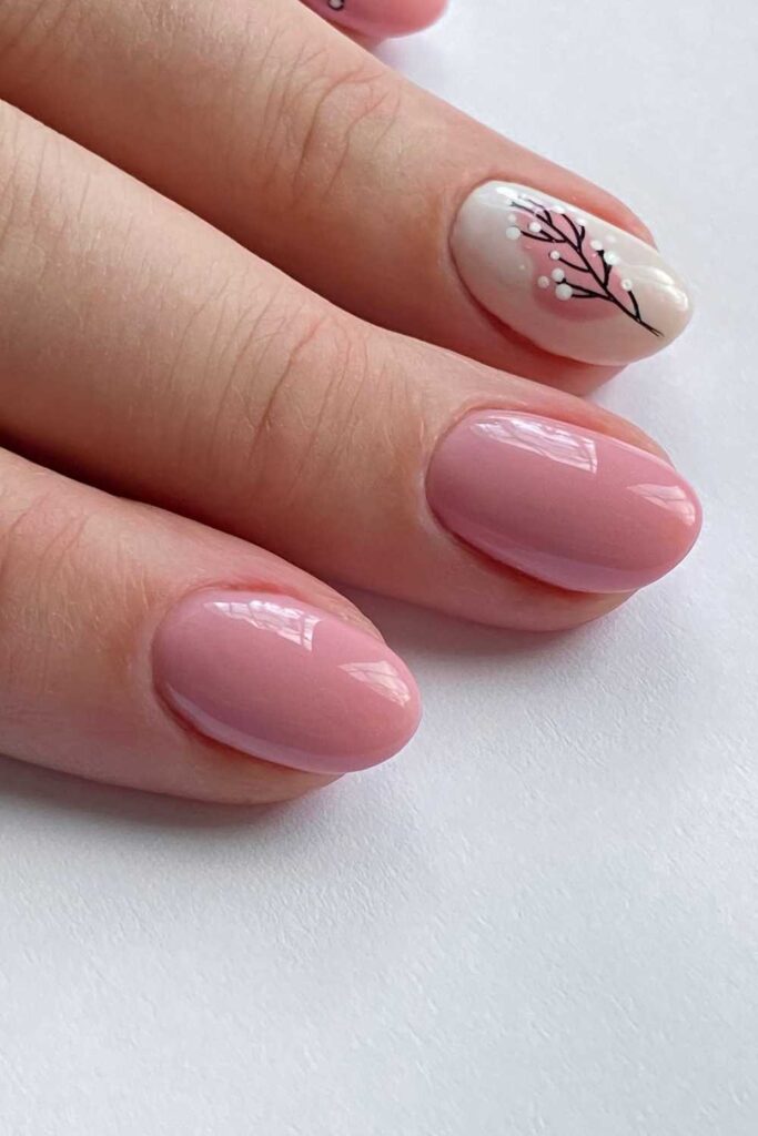 Nude pink nails design with a flowered design on the fore finger
