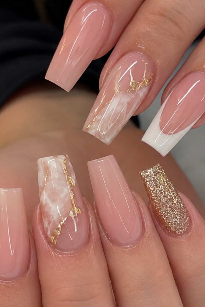 A nude a acrylic nail design with a touch of golden design.