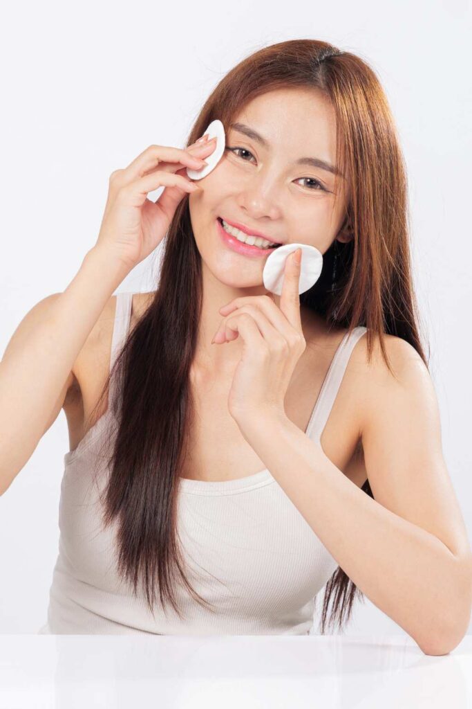 Skin prepping of a lady using cotton to wipe her face.