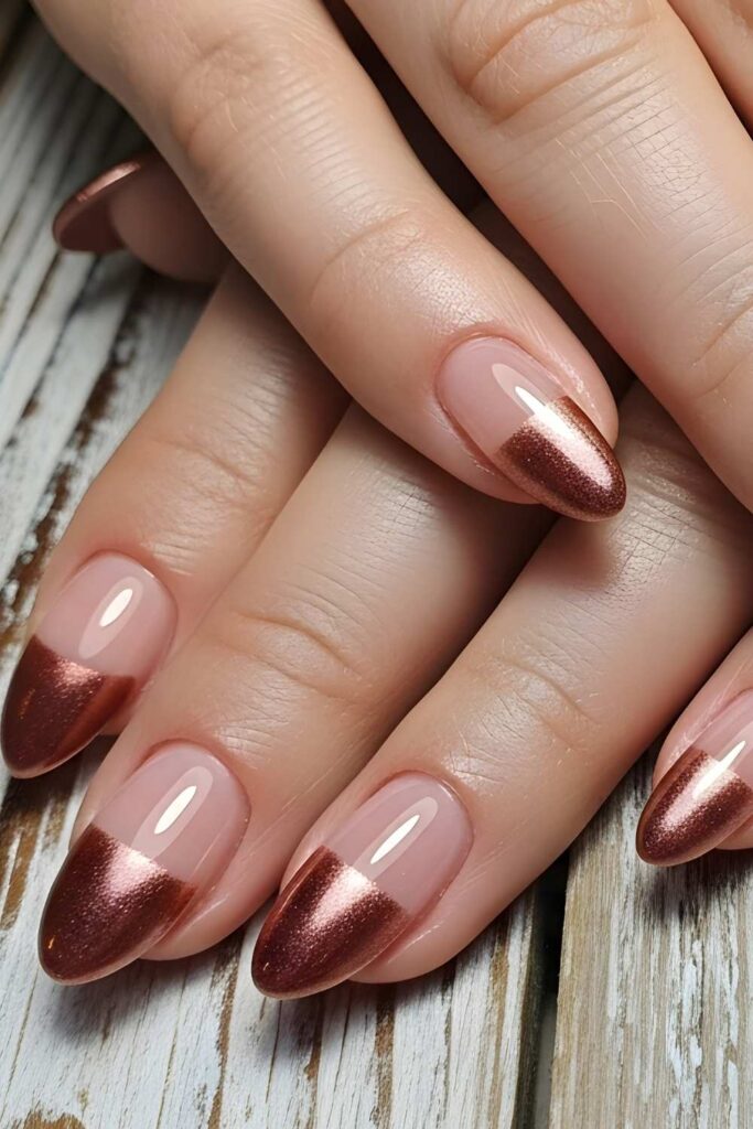 A picture of French tip nails that looks gorgeous of nude and shiny brown tips
