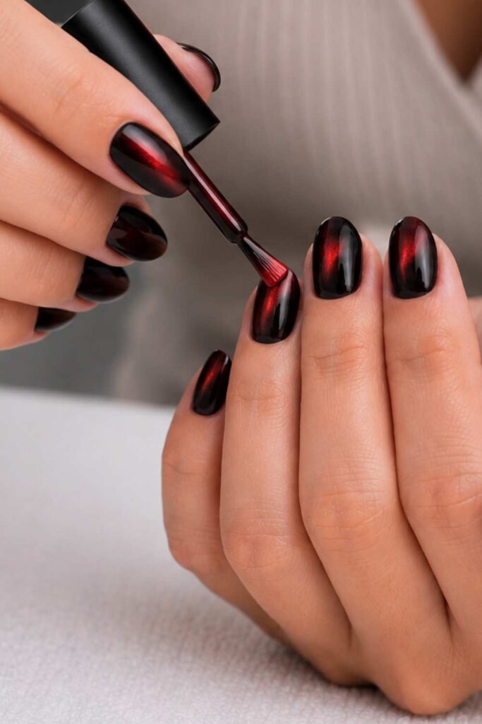 Applying a red coat on the black nail color for the cat-eye design