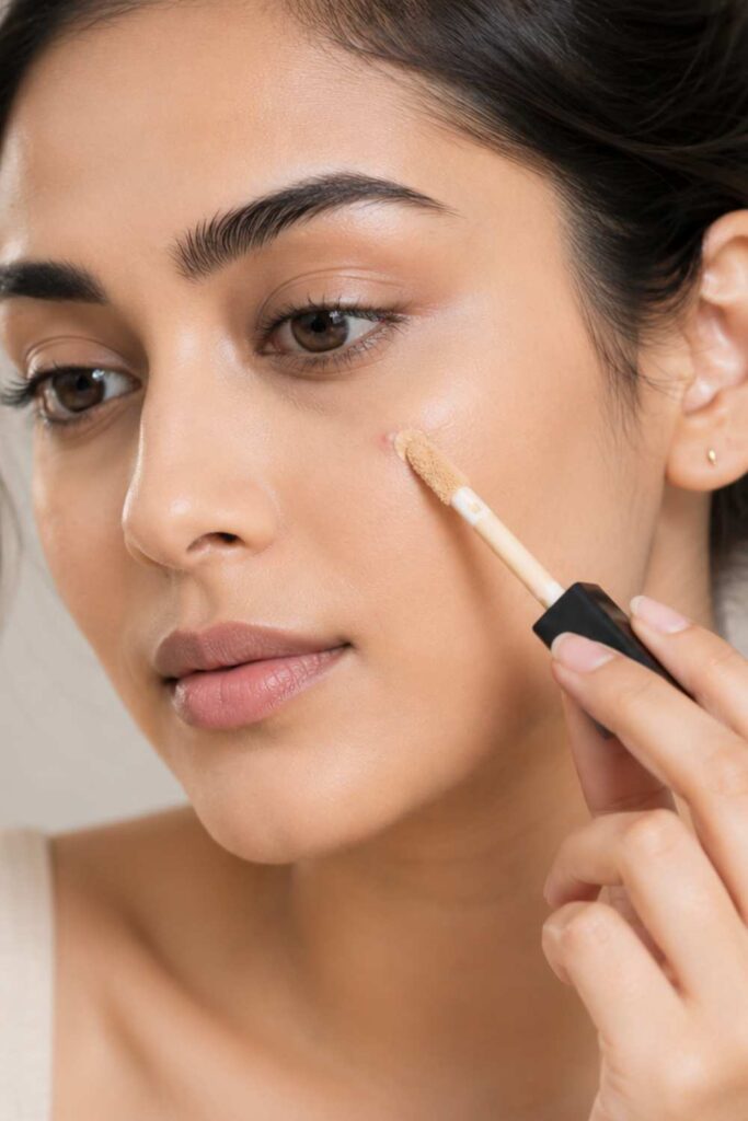 A lady using concealer to cover spot area